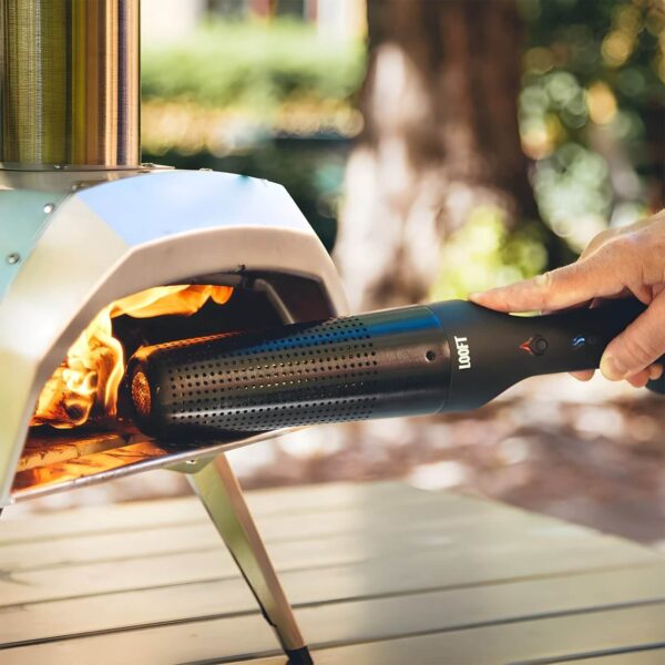 Mano usando el encendedor eléctrico Looft Lighter X para encender un horno de pizza de leña al aire libre.