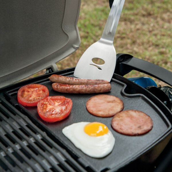 Desayuno cocinado en una Plancha de Hierro Colado Q 1000 de Weber, con salchichas, tomate, jamón y un huevo frito.