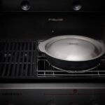 Wok de Weber con tapa de acero inoxidable en una barbacoa Weber Genesis, preparado para cocinar al vapor.