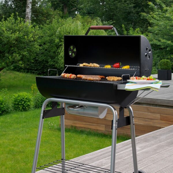 Barbacoa LANDMANN Black Taurus 660 en uso, con alimentos asándose y una mesa lateral que muestra la practicidad del diseño.