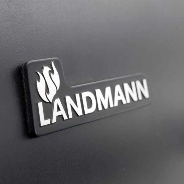 Logotipo de LANDMANN en primer plano en la tapa de la barbacoa Black Taurus 660, destacando la marca y la calidad del producto.