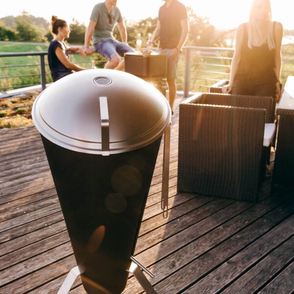 Barbacoa CONE de Höfats cerrada en una terraza con amigos disfrutando de un atardecer juntos.