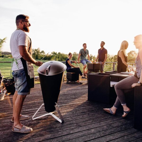 Amigos reunidos en una terraza con una barbacoa de carbón CONE de Höfats, disfrutando de una tarde de asado.