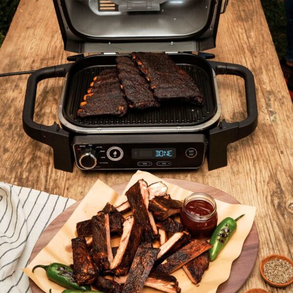 Barbacoa eléctrica Ahumador Woodfire en uso, mostrando una jugosa preparación de costillas ahumadas sobre la parrilla, listas para servir.