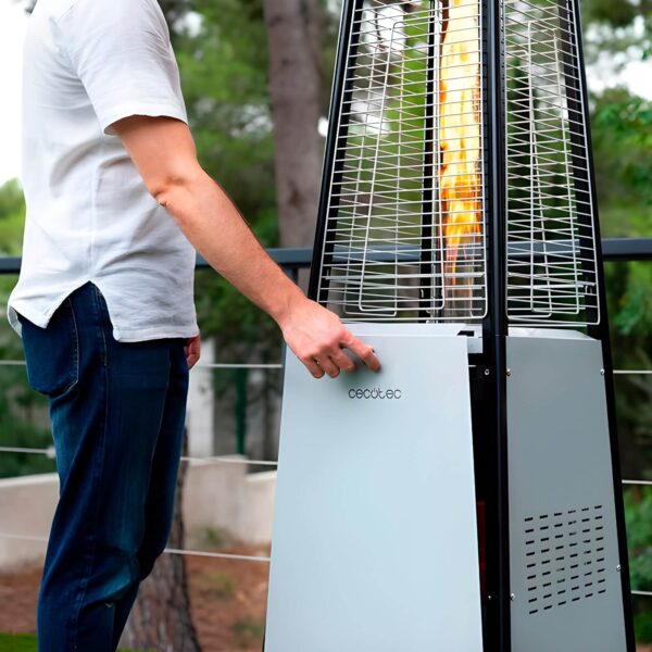 Persona ajustando la estufa de gas Cecotec ReadyWarm 8900 en un jardín.