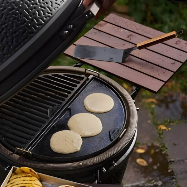 Pancakes cocinándose en una plancha de hierro fundido dentro de una parrilla al aire libre.