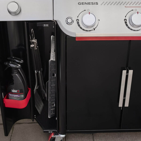 Compartimiento de almacenamiento lateral en la barbacoa Weber Genesis EP-335W con utensilios y productos de limpieza organizados.