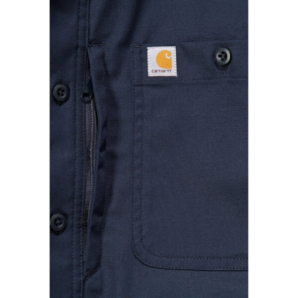 Detalle del bolsillo con cremallera y logo de la camisa de trabajo Carhartt en color azul marino.