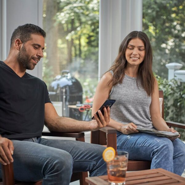 Pareja relajada monitoreando la cocción en un smartphone mientras disfrutan de su tiempo libre.