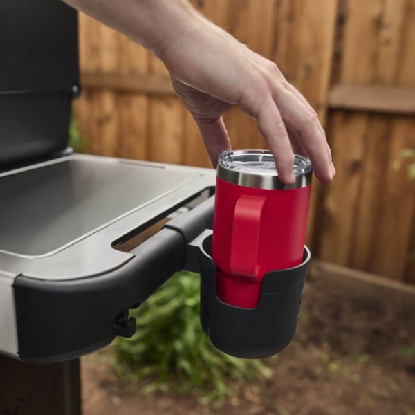 Persona colocando una taza roja en el Porta Botellas Acoplable Works - Weber instalado en una parrilla.