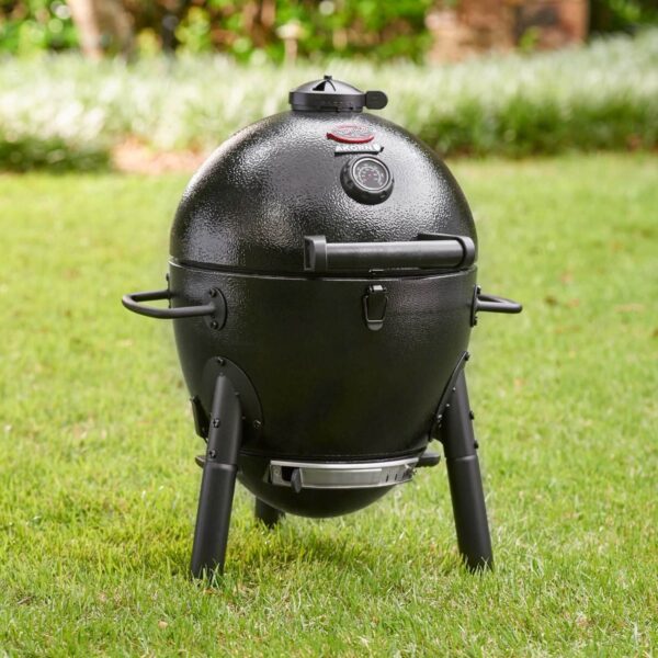 Kamado Akorn Junior de CharGriller en un jardín, con su diseño compacto y termómetro visible en la tapa.