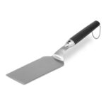 Weber stainless steel spatula with non-slip handle and raised design for use on griddles and grills.