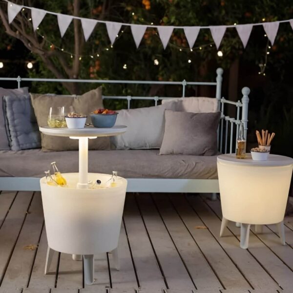 Dos mesas nevera CoolBar de Keter iluminadas con LED en una terraza nocturna, con bebidas y aperitivos en un ambiente acogedor.