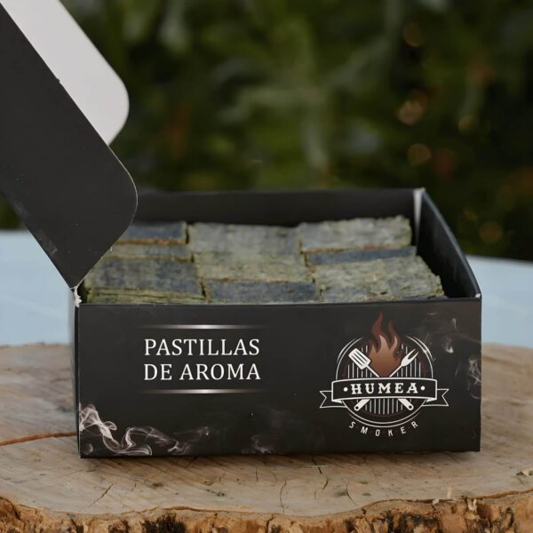 Caja abierta de pastillas aromáticas Humea Smoker, mostrando su contenido compacto y uniforme, ideal para ahumar alimentos de manera natural y eficiente.