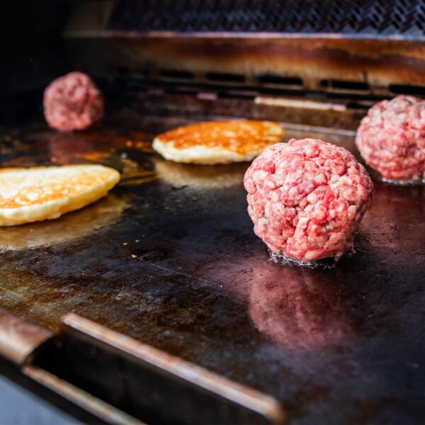 Bolas de carne y panqueques cocinándose en la plancha de acero inoxidable Napoleon sobre una parrilla Prestige PRO, Prestige, Built-in 700, Rogue 525 o 625.