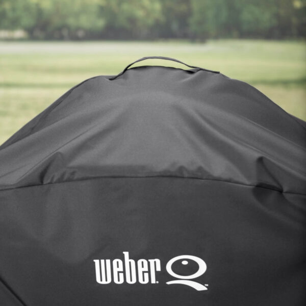 Detalle de la funda Weber® Premium Q3000/Q2000 con carro, mostrando el asa superior y el logo blanco sobre el material negro resistente.