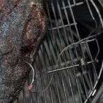 Sonda de temperatura Weber midiendo la cocción de un corte de carne en una parrilla.