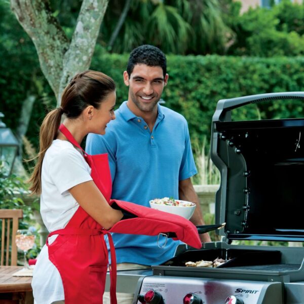 Pareja cocinando en una barbacoa Weber Spirit con la Plancha Deluxe, preparando mariscos en un entorno al aire libre.