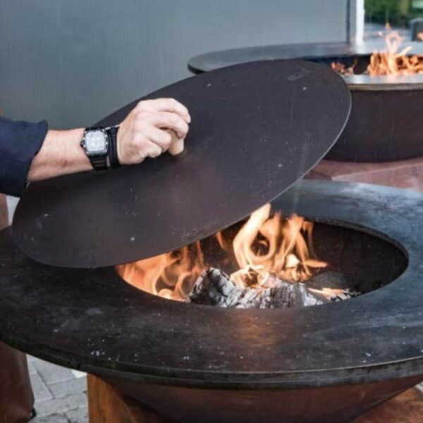 Persona utilizando la tapa apaga fuegos OFYR para extinguir brasas en una parrilla de exterior.