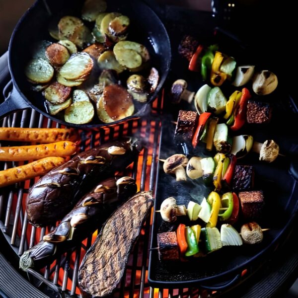 Brochetas de verduras, berenjenas asadas, salchichas y patatas cocinadas en una parrilla con plancha de hierro fundido.