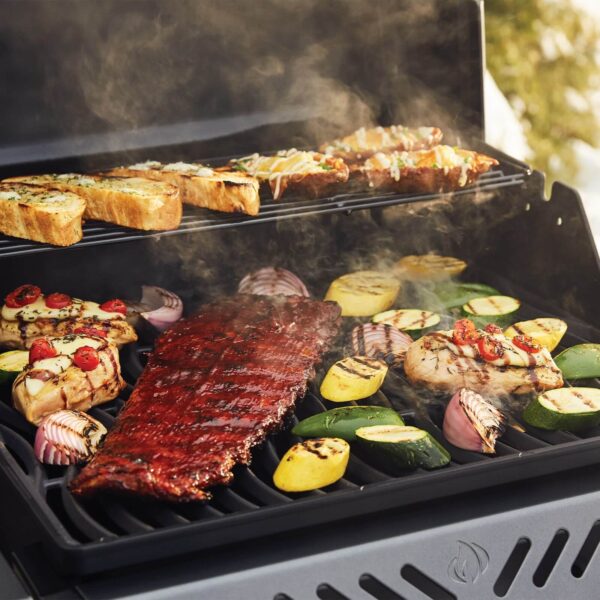 Parrilla en funcionamiento con costillas, pollo y vegetales como calabacines, papas y cebollas asándose al aire libre.