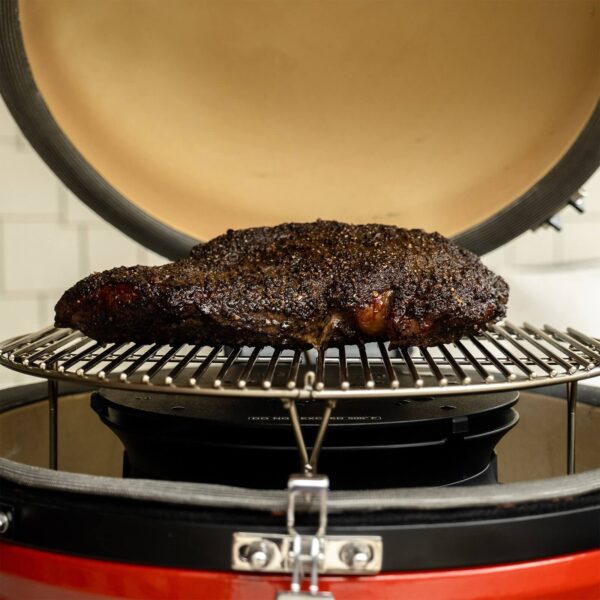 Carne cocinándose en la cámara de humo SlōRoller Classic Joe dentro de una parrilla Kamado Joe.