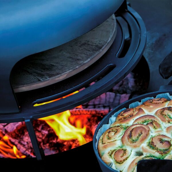 Horno de pizza OFYR con leña encendida, mostrando un pastel salado en proceso de cocción, destacando el calor uniforme y la versatilidad del horno.