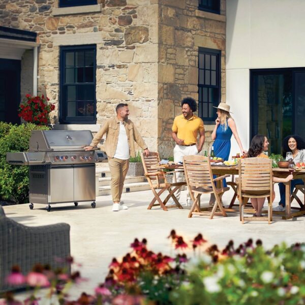 Grupo de amigos disfrutando de una reunión al aire libre con la barbacoa Napoleon Prestige 665 Connected RSIB en una terraza moderna.