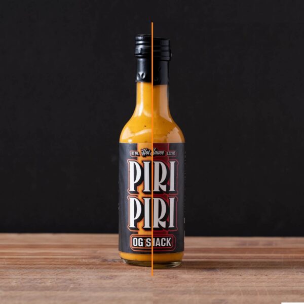 Botella de salsa Piri Piri OG Shack en niveles Hot y Mid, 187 ml, destacada sobre fondo oscuro de madera.