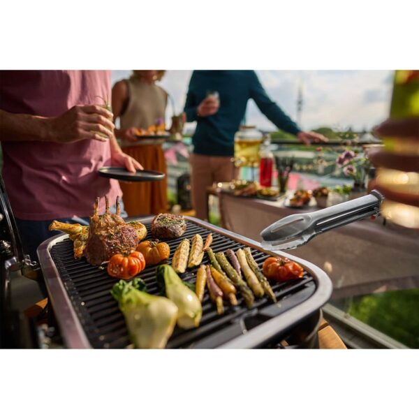 Personas disfrutando de una parrillada con la barbacoa eléctrica Lumin de Weber, cocinando carne y vegetales.