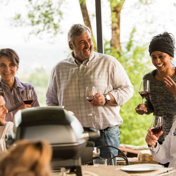 Grupo de personas riendo y disfrutando de una reunión con la parrilla Napoleon TravelQ Pro 285 al aire libre.