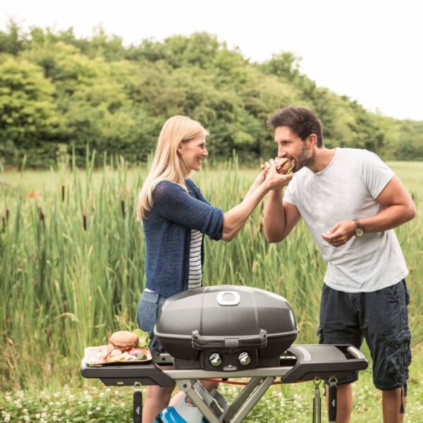 Grupo de amigos disfrutando de una parrillada con la Napoleon TravelQ PRO285 en un entorno natural.