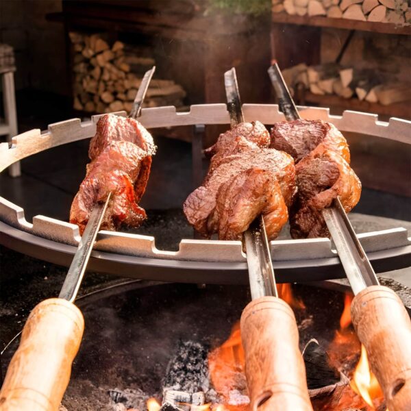 Brochetas de carne asándose sobre un set OFYR, cocinadas al fuego directo para lograr un sabor ahumado.