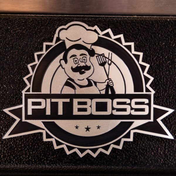 Logotipo de Pit Boss en relieve sobre la superficie de la barbacoa, con un chef sosteniendo utensilios de parrilla.