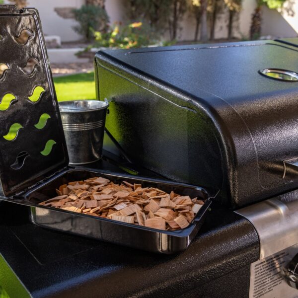 Bandeja de astillas de madera abierta en la barbacoa Pit Boss Memphis V2, lista para el proceso de ahumado.