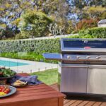 Barbacoa Beefeater Signature S2000 5B con carro en terraza de madera junto a piscina