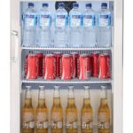 Nevera Beefeater de una puerta con interior iluminado, llena de botellas de agua, latas de refresco y cervezas frías.