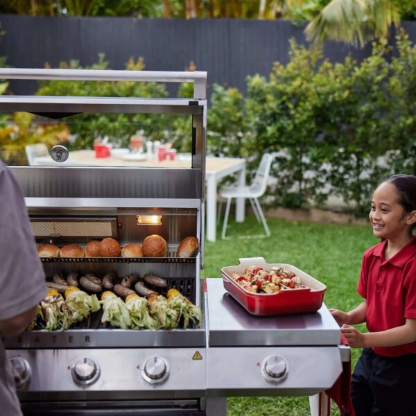 Beefeater Signature 7000 en funcionamiento con alimentos a la parrilla en un jardín.