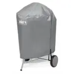 Barbacoa Weber Kettle de 57 cm cubierta con su funda protectora y el logotipo Weber visible.