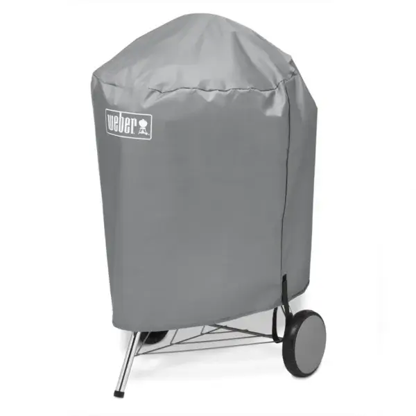 Barbacoa Weber Kettle de 57 cm cubierta con su funda protectora y el logotipo Weber visible.