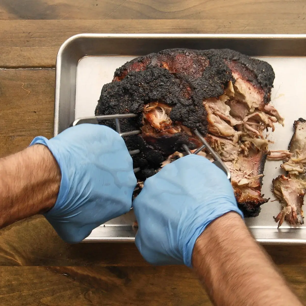 Uso de las dos garras Char-Griller para separar carne de cerdo cocinada