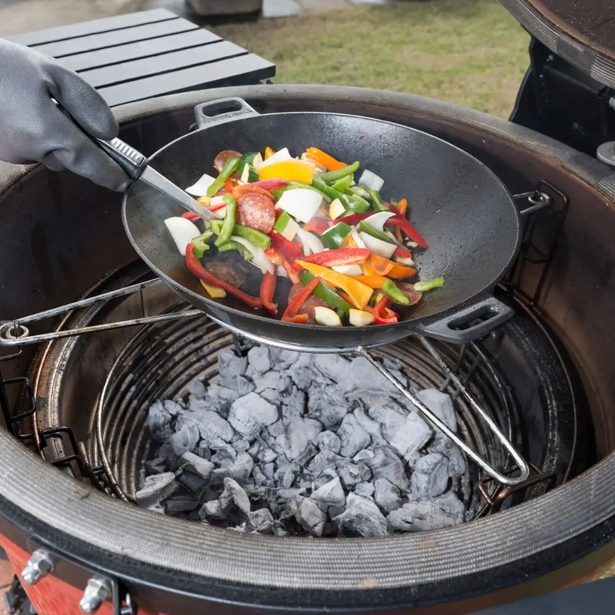 Wok con verduras colocado sobre el soporte para sartén Kamado Joe
