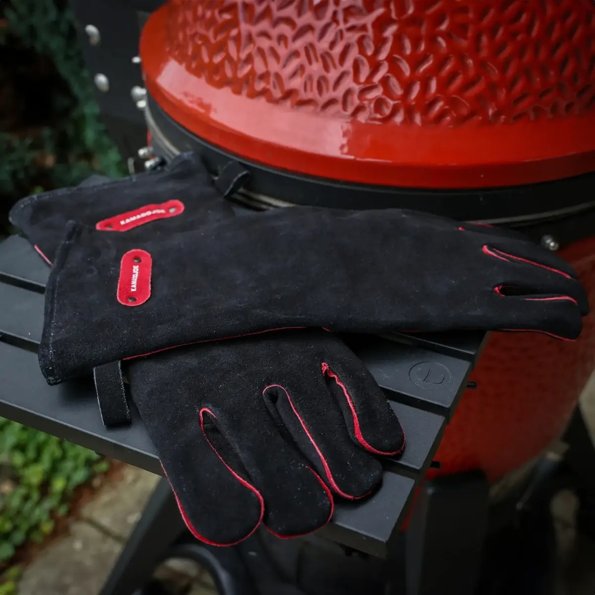 Guantes de cuero Kamado Joe sobre la mesa lateral de una barbacoa
