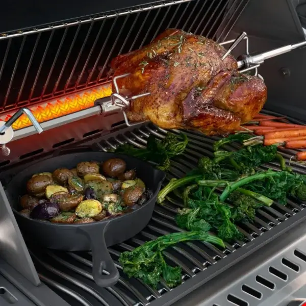 Detalle de la Napoleon Prestige PRO 500 VX sellando carne en la SIZZLE ZONE con una mano usando pinzas.