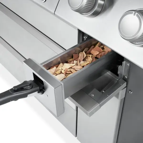 Detalle de la caja ahumadora de la parrilla Napoleon Prestige PRO 665 Elite con astillas de madera en el interior.