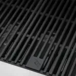 Detalle de las parrillas de hierro fundido de la GrandPro Maxim G5 con emblema de llama.