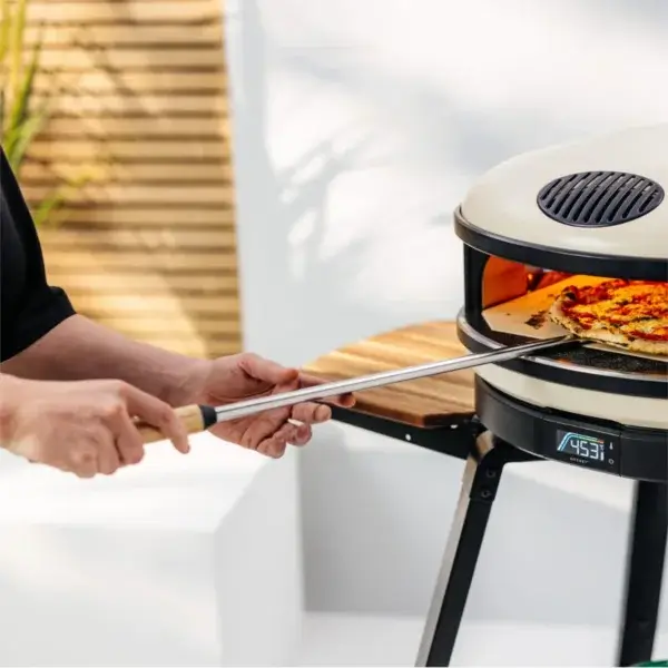 Manos usando la pala Gozney Balance para mover una pizza dentro de un horno Gozney.