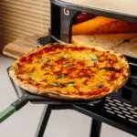 Pizza cocinada sobre una pala Gozney Pro Peel 16 XL frente a la boca de un horno Gozney.