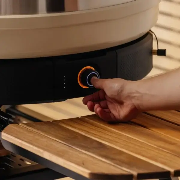 Mano ajustando el mando del módulo Gozney Wood-Fire Control Kit instalado bajo un horno Dome.