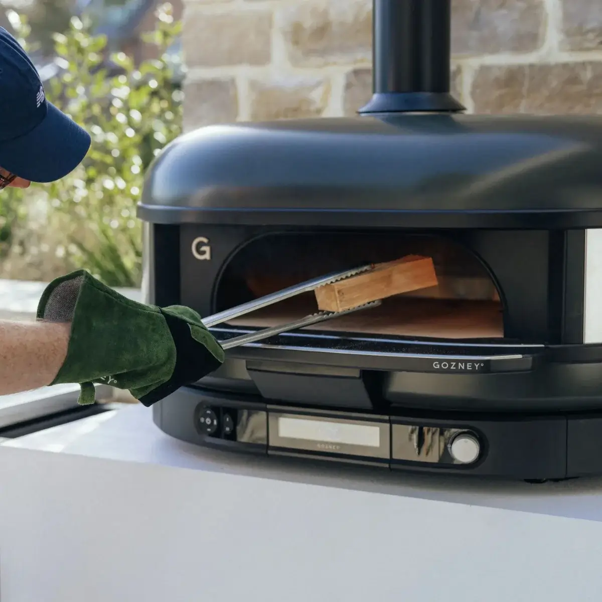 Pinzas Gozney para combustible y horno Pinzas Gozney junto a un horno de leña exterior